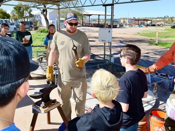 Adult teaching blacksmith skills to teens