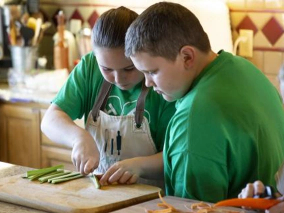 Two kids chopping vegetables