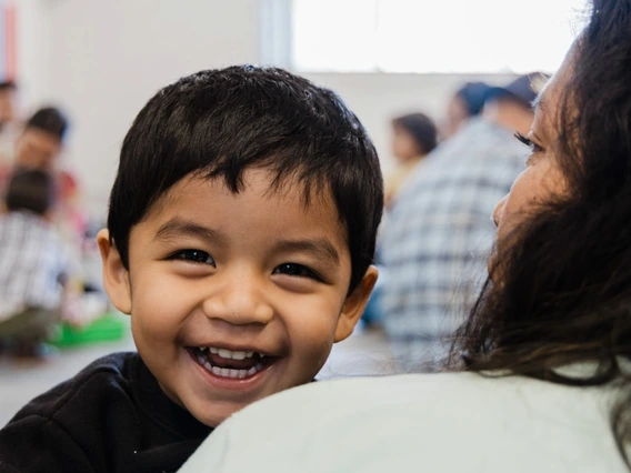 child smiling on mom shoulder