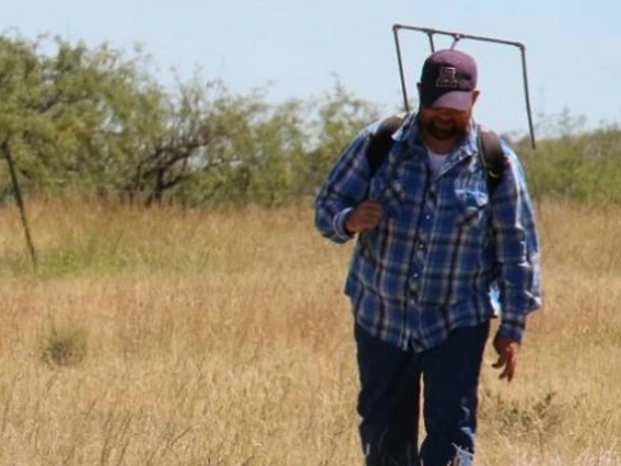 extension agent walking through range with vegetation square