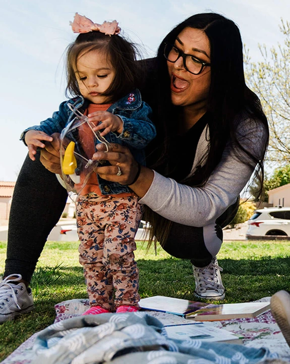 mother on picnic blanket in park playing with her small children