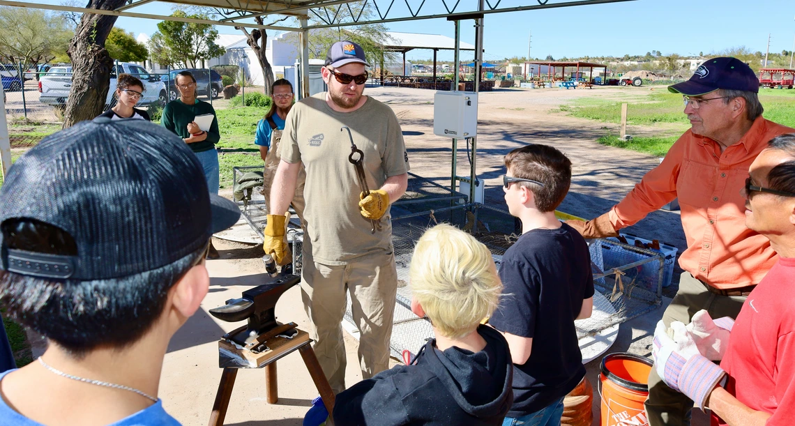 Adult teaching blacksmith skills to teens