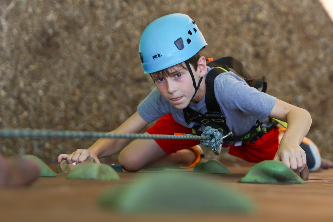 Teen boy climbing rock wall