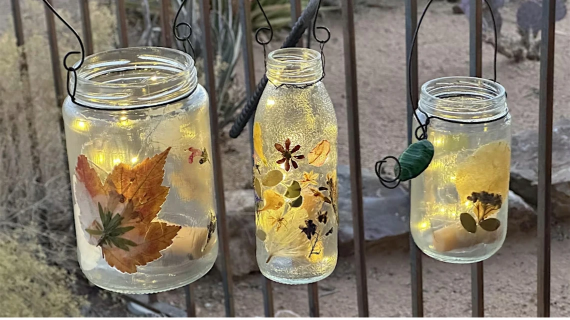 leaves and flower pressed onto jars with lights inside