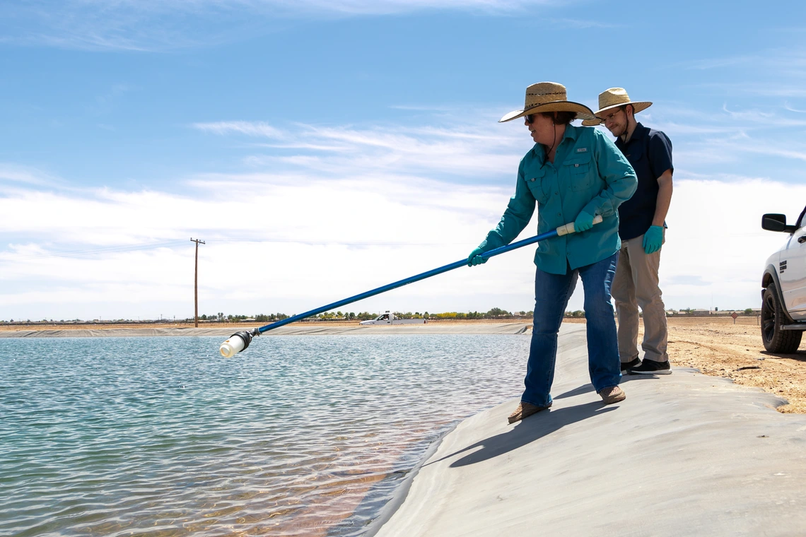 researcher collecting water from ag basin