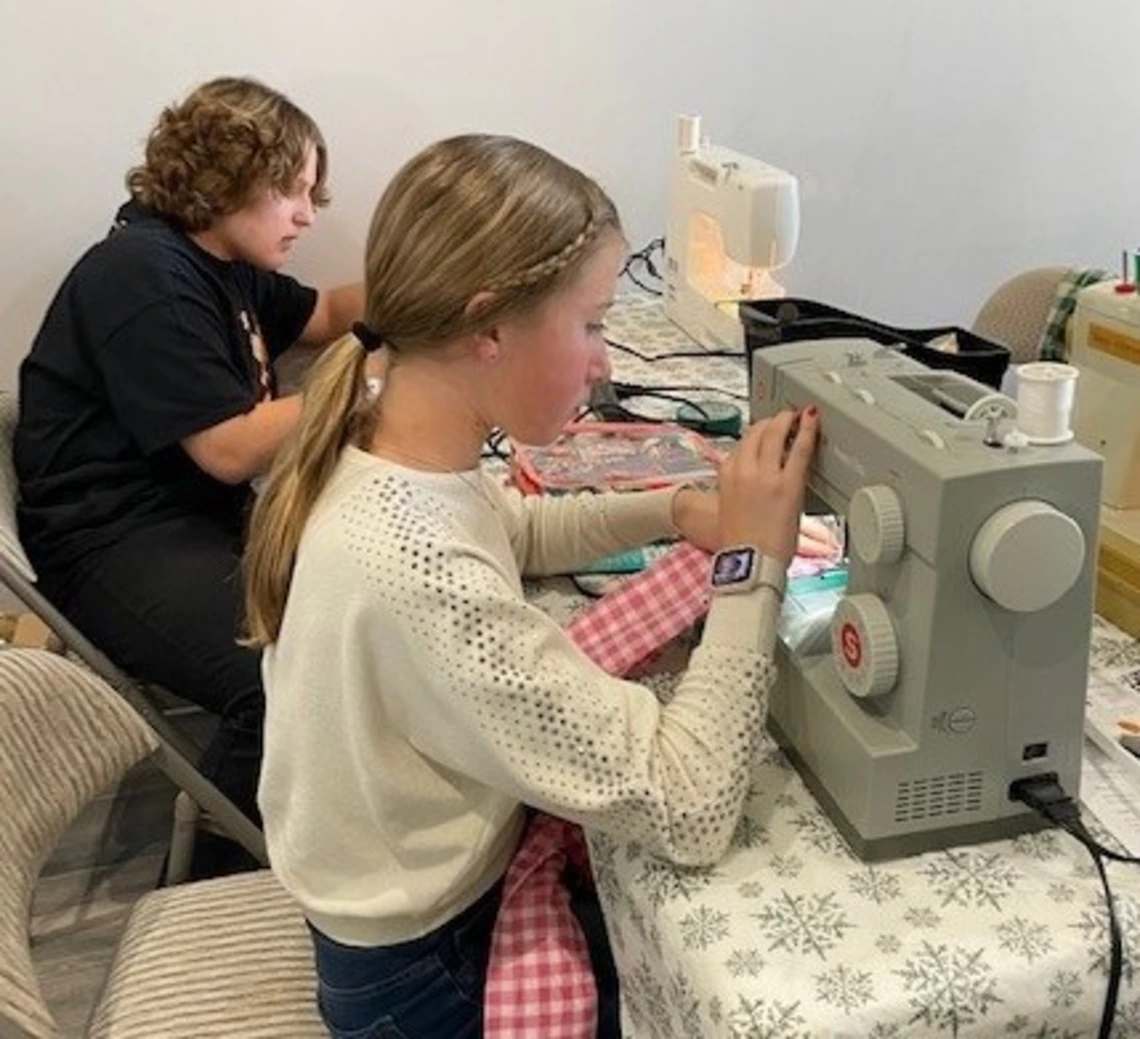 young girl sewing using a machine