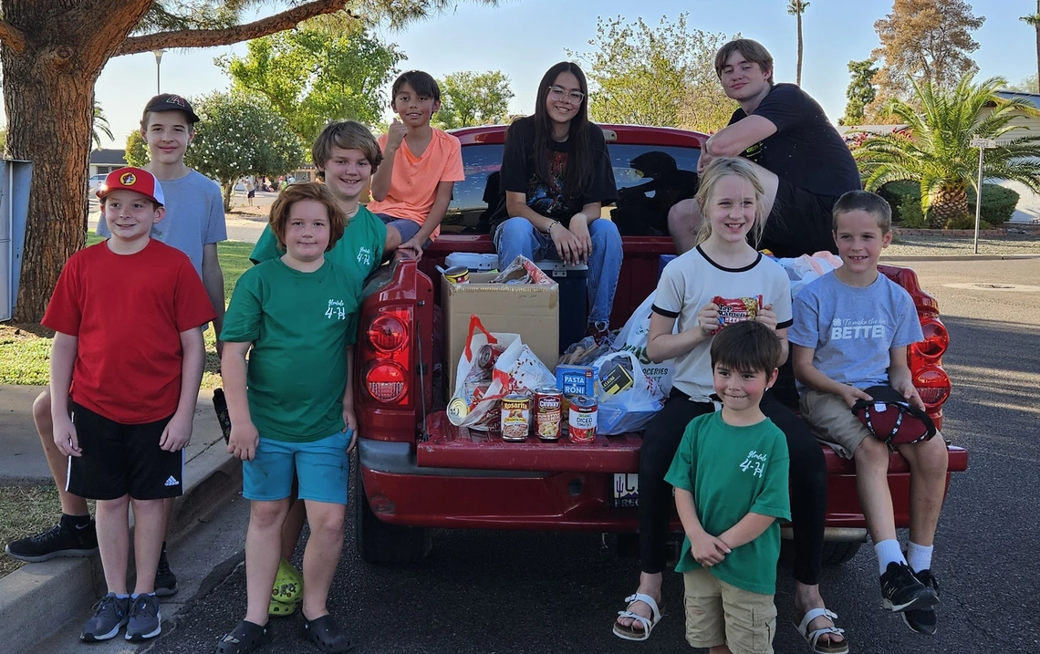 4-H youth sitting on pickup truck donating food