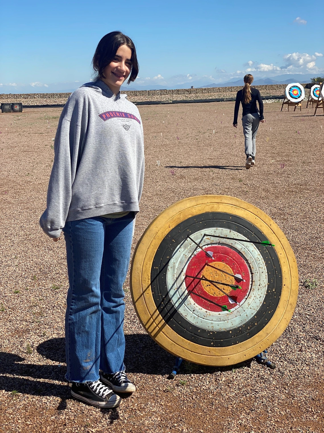 young girl next to archery target with arrow