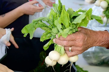 Photo of a person handing vegetables to another person