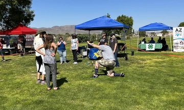 Event participants standing in a ring in grass with vendor booths in background